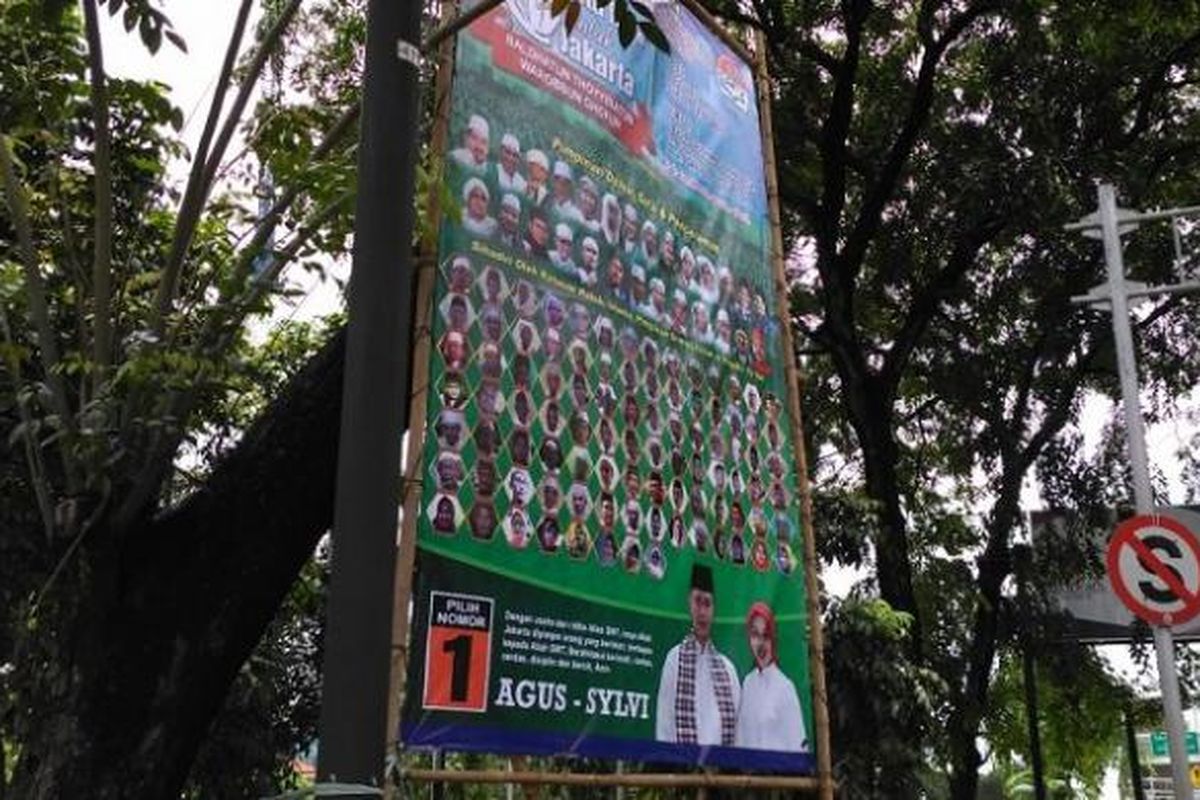 Spanduk yang antara lain berisi ajakan utuk memilih pasangan calon gubernur dan wakil gubernur DKI Jakarta nomor pemilihan satu, Agus Harimurti Yudhoyono dan Sylviana Murni, masih terpasang di sepanjang Jalan Daan Mogot, Jakarta Barat, Minggu (12/2/2017). Spanduk masih terpasang pada hari pertama masa tenang tahapan Pilkada DKI 2017.