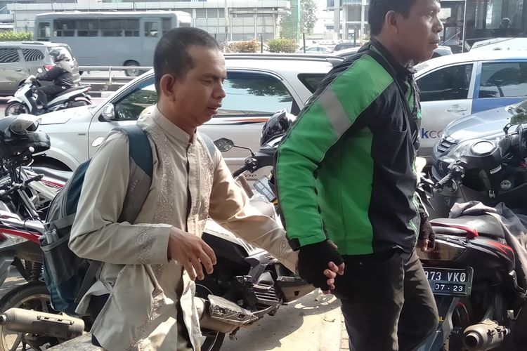 Zulkifli gandeng penumpangnya yang tuna netra ke dalam gedung Kemenaker, Jakarta Selatan, Kamis (31/10/2019)
