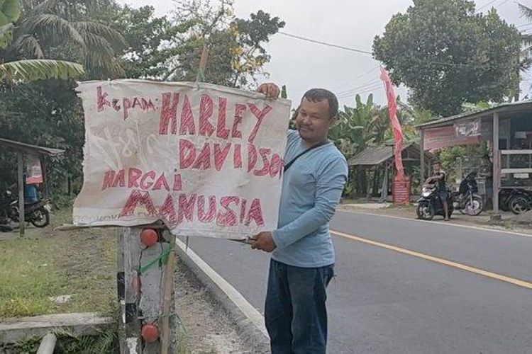 Warga memperhatikan tulisan di spanduk setelah kecelakaan maut yang mengakibatkan dua bocah kembar meninggal dunia. 
