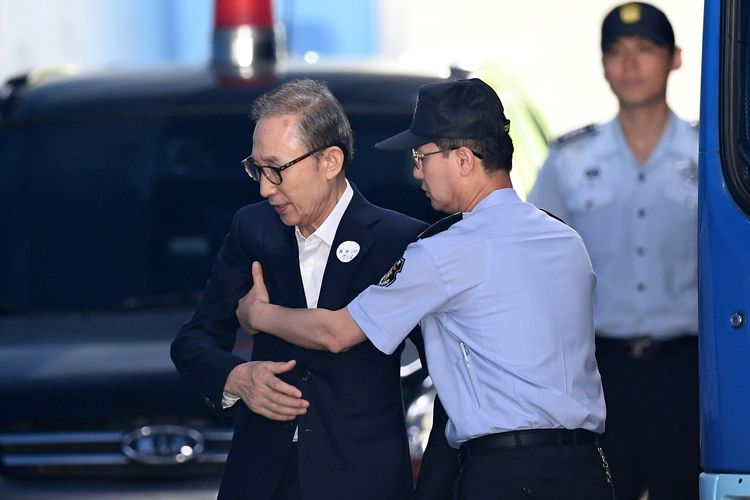 Eks presiden Korea Selatan Lee Myung-bak (kiri) dikawal penjaga penjara saat tiba di pengadilan untuk menghadiri persidangan pertamanya pada 6 September 2018 di Seoul. Lee dijatuhi hukuman penjara 17 tahun karena penggelapan dana dan penyuapan.