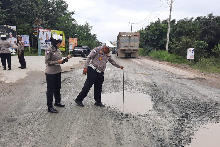 Petugas Ditlantas Polda Riau menemukan salah satu titik jalan lintas yang mengalami kerusakan cukup parah di Provinsi Riau, Sabtu (16/12/2023).