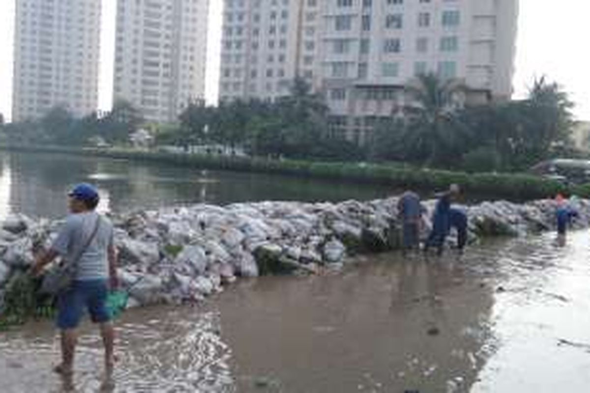 Petugas gabungan bekerja sama menutup tanggul Pantai Mutiara, Penjaringan, Jakarta Utara, yang jebol dengan menggunakan kantong berisi pasir, Sabtu (4/6/2016).