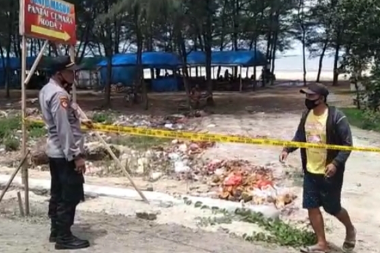 Kapolsek Jenu, Tuban, AKP Rukimin memasang garis polisi untuk menutup akses masuk lokasi wisata pantai cemara, Kabupaten Tuban, Jawa Timur. Minggu (25/10/2020)