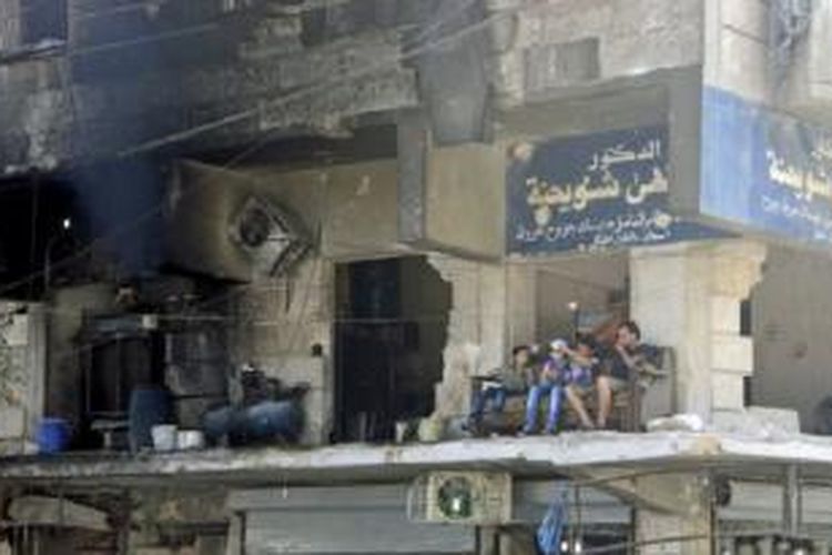 Warga duduk di balkon sebuah bangunan yang rusak berat di kawasan al-Shaar, di Aleppo, Suriah bulan Agustus lalu.