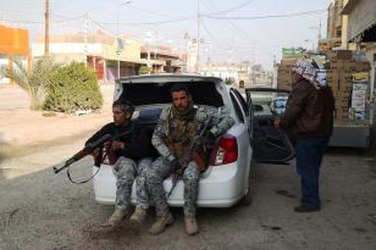 Polisi Irak terlihat bersama dengan seorang anggota milisi kesukuan di salah satu sudut kota Ramadi, Provinsi Anbar. Sejak beberapa hari terakhir baku tembak terjadi di kota itu antara para pejuang Negara Islam Irak dan Mediterania Timur (ISIL) dan pasukan Irak yang didukung milisi kesukuan.