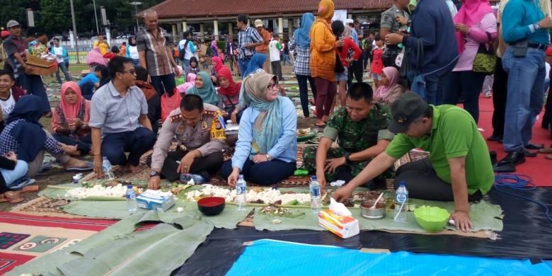 Bupati Pandeglang Irna Narulita (tengah) didampingi Kepala Kepolisian Resor Pandeglang Ajun Komisaris Besar Ary Satriyan, Komandan Kodim 0601/Pandeglang Letnan Kolonel Inf Ganiahardi, dan Ketua DPRD Pandeglang Gunawan menikmati hidangan di atas daun pisang di Alun-alun Pandeglang, Banten, Sabtu (31/12). Mereka bersama ratusan warga Pandeglang melakukan tradisi khas Pandeglang, yakni papahare atau membawa makanan untuk ditukar dan disantap bersama-sama.