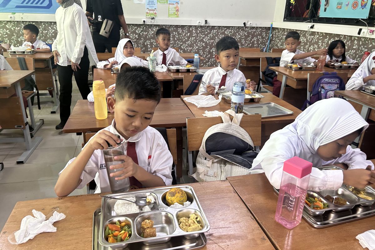 Momen ketika siswa SD Negeri Susukan 01/02  Ciracas, Jakarta Timur, mengkonsumsi Makan Bergizi Gratis dengan menu nasi, telur, tumis buncis dan wortel, tempe goreng, serta jeruk pada Selasa (7/1/2025).