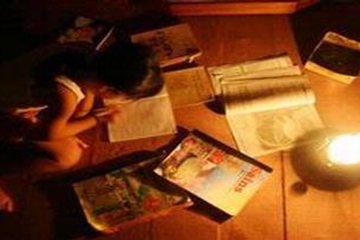Seorang anak terpaksa belajar menggunakan lampu minyak karena listrik padam.