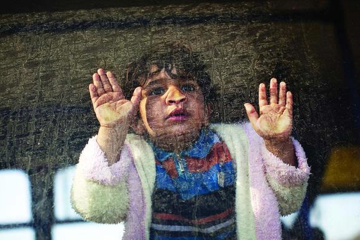 Ahmed (2 tahun), seorang anak laki-laki Mesir, melihat ke luar melalui jendela bus saat ia dan keluarganya, yang bekerja di Libya, meninggalkan negara itu, di luar perbatasan Tunisia-Libya di wilayah Ras Ajdir, Tunisia, Kamis.