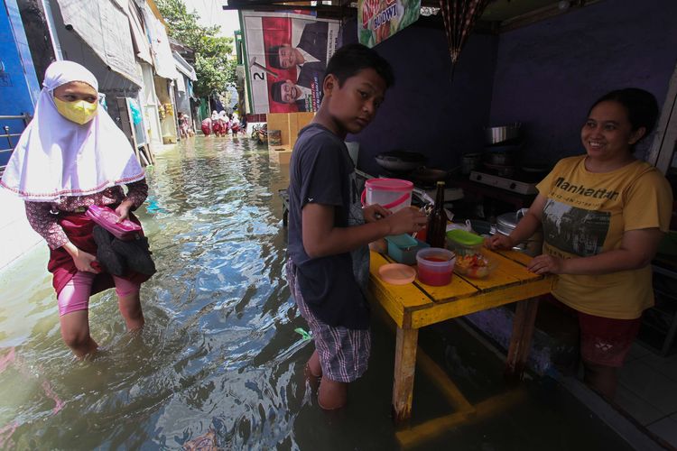 Pelajar berjalan melintasi banjir rob yang menggenangi kampung di kawasan Kalianak Timur, Surabaya, Jawa Timur, Kamis (19/5/2022). Pasang air laut yang tinggi menyebabkan perkampungan padat penduduk di kawasan itu tergenang banjir rob.
