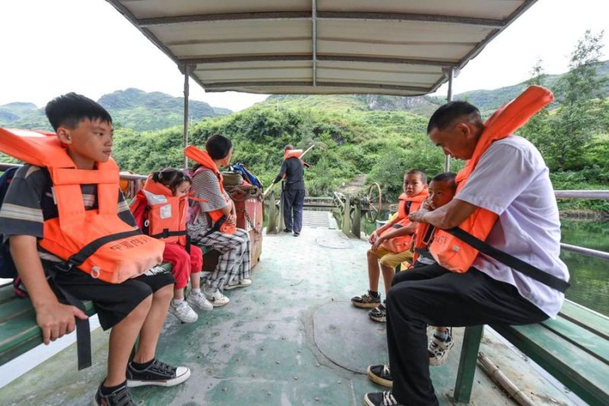 Guru bernama Ren Dabing (pertama dari kanan) dan murid-muridnya menaiki perahu feri saat perjalanan pulang dari sekolah di Desa Wansen, Kota Yajia, Wilayah Otonom Etnis Miao Songtao, Provinsi Guizhou, China barat daya, pada 9 September 2025.