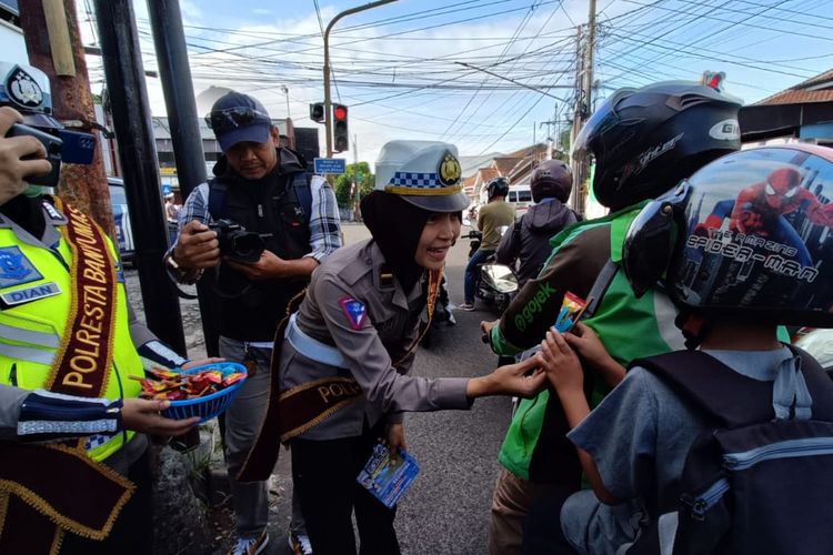 Polwan membagikan coklat kepada anak-anak yang tertib berlalu lintas saat sosialiasi keselamatan lalu lintas Operasi Candi 2023 di simpang Karangkobar, Purwokerto, Kabupaten Banyumas, Jawa Tengah, Selasa (14/2/2023). 