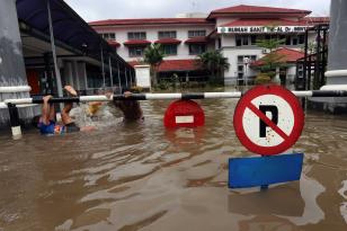 Sejumlah bocah bermain di depan RS AL Mintohardjo, Bendungan Hilir, Jakarta Pusat, yang tergenang banjir, Rabu (29/1/2014). Hujan deras yang menguyur sejak kemarin malam membuat sejumlah titik di Jakarta kembali tergenang banjir. WARTA KOTA/ANGGA BHAGYA NUGRAHA