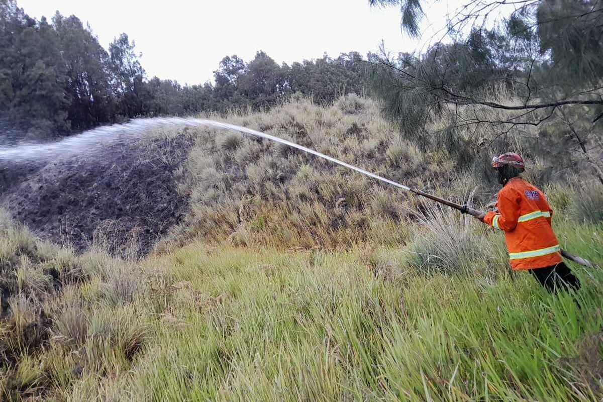 Tim gabungan BPBD melakukan pembasahan di area terbakar Gunung Bromo.