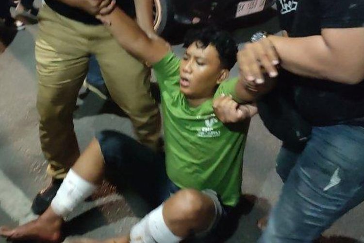 Salah satu begal yang menewaskan mahasiswa UMSU saat dibawa masuk ke Markas Kepolisian Resor Kota Besar Medan pada Selasa (20/6/2023) malam.