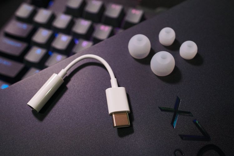 Adapter jack audio 3,5mm ke USB C dan dua pasang eartips berbeda ukuran yang menyertai earphone in-ear di kemasan Vivo X70 Pro