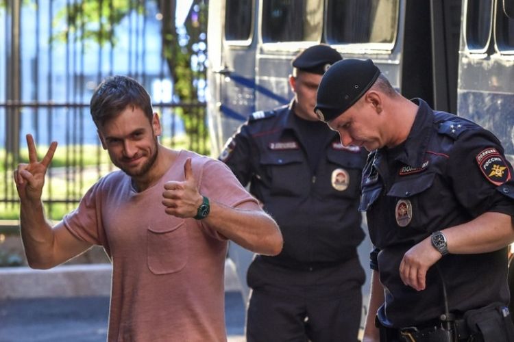 Anggota dari kelompok punk Pussy Riot, Pyotr Verzilov, berjalan dengan polisi selama sidang pengadilan di gedung pengadilan di Moskwa, Rusia, pada 31 Juli 2018. (AFP/Vasily Maximov)