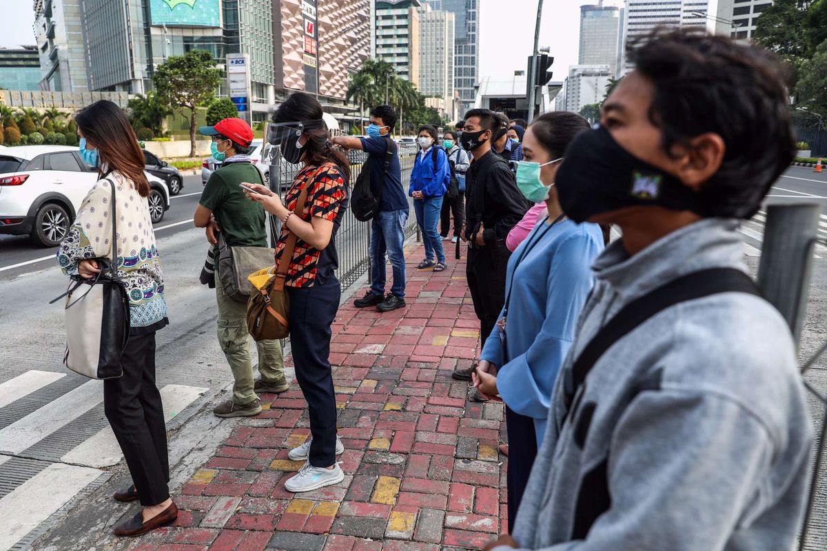 Pekerja yang menggunakan masker saat menunggu menyebrangi zebra cross di Jalan M.H Thamrin, Jakarta Pusat, Senin (14/9/2020). PSBB kembali diterapkan tanggal 14 September 2020, berbagai aktivitas kembali dibatasi yakni aktivitas perkantoran, usaha, transportasi, hingga fasilitas umum.