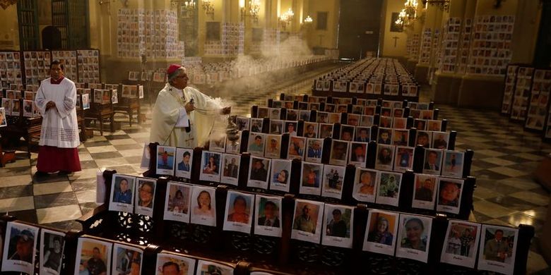 Uskup Agung Lima, Carlos Castillo, ketika memberkati foto korban meninggal Covid-19 saat memimpin misa Minggu di katedral Peru (14/6/2020).