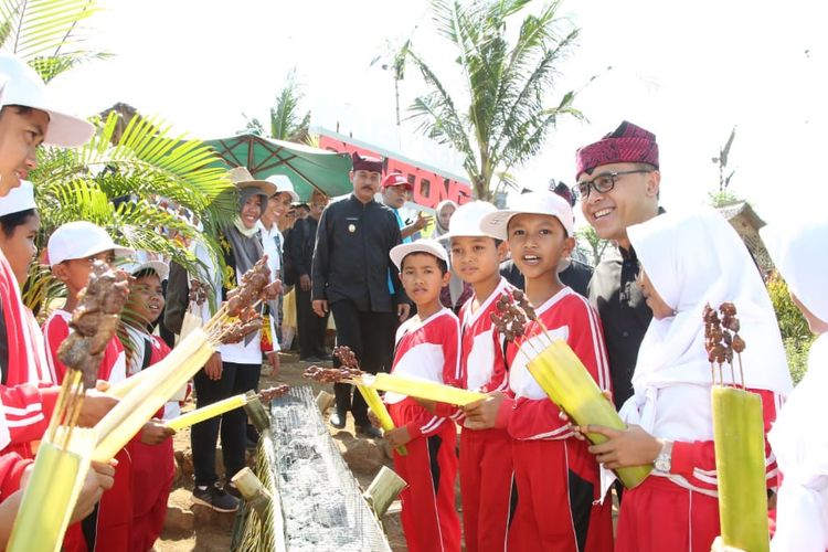 Ribuan siswa siswi Sekolah Dasar (SD) menikmati puluhan ribu sate ayam dan kambing, serta susu sapi segar dalam acara Tamansuruh Farm Festival, di kawasan Agrowisata Tamansuruh, Kecamatan Glagah, Banyuwangi, Selasa (23/10/2019)