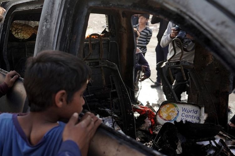 Orang-orang berkumpul di sekitar mobil yang digunakan oleh kelompok bantuan World Central Kitchen yang berbasis di AS, yang terkena serangan Israel sehari sebelumnya di Deir al-Balah di Jalur Gaza tengah pada 2 April 2024.