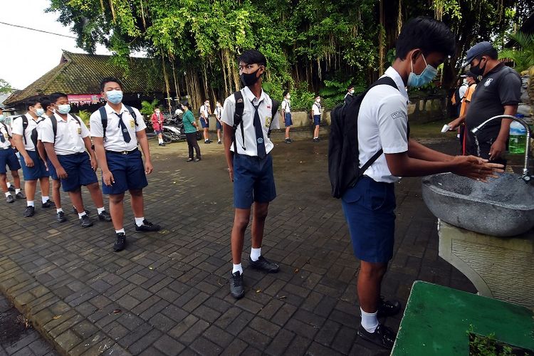 Students at the State Hindu Junior High School no. 2 in Sukowati district in Gianyar regency, Bali wash their hands before entering the school for face-to-face classes on Tuesday (23/3/2021). The regency administration held tight health protocols and limited the number of students in each classroom to 20. They also split the classes into two sessions between 7:30 am to 9:30 AM local time, and from 10: am to 12 pm. ANTARA FOTO/Nyoman Hendra Wibowo/aww.