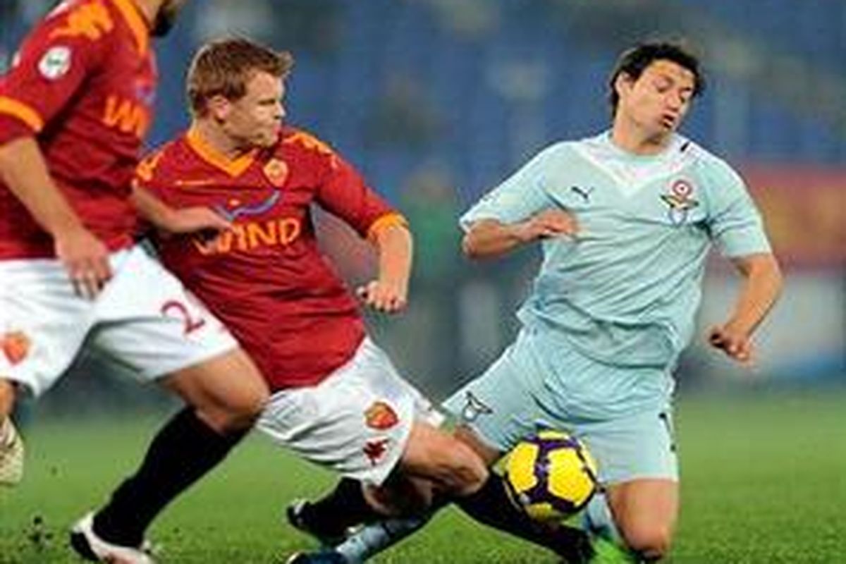 Bek AS Roma, John Arne Riise (tengah) mencoba merebut bola dari penyerang Lazio, Mauro Zarate, dalam duel lanjutan Serie-A, Minggu (6/12).