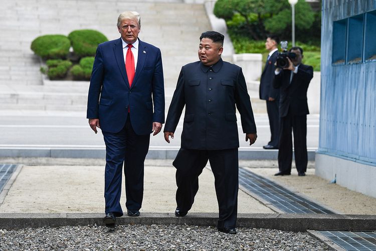 Pemimpin Korea Utara Kim Jong Un (kanan) dan Presiden AS Donald Trump melintasi Garis Demarkasi Militer yang membagi Korea Utara dan Korea Selatan di zona demiliterisasi (DMZ) Korea, Minggu (30/6/2019). Kedatangan Trump ke zona demiliterisasi Korea awalnya diagendakan untuk pertemuan dengan Presiden Korea Selatan Moon Jae-in, namun Presiden Moon mengatakan fokus akan lebih kepada pertemuan Trump dengan Kim Jong Un.