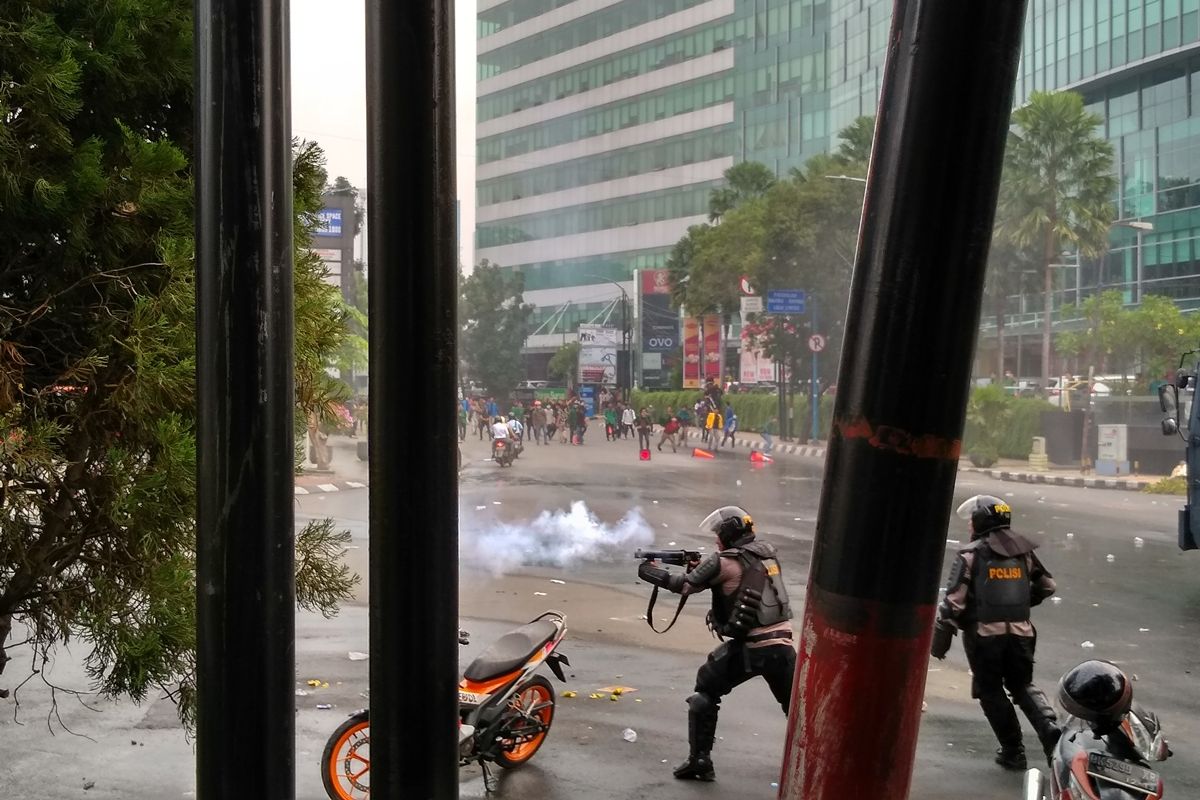 Seorang polisi menembakkan gas air mata ke arah massa aksi yang berhamburan setelah rusuh di depan gedung DPRD Sumut, Selasa sore tadi (24/9/2019).