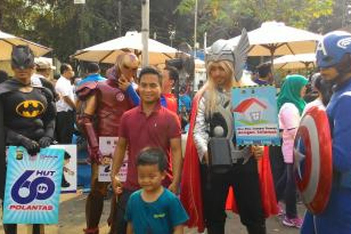 Sejumlah masyarakat berfoto dengan superhero pada acara HUT Polantas di kegiatan Car Free Day (CFD), Minggu (27/9/2015).