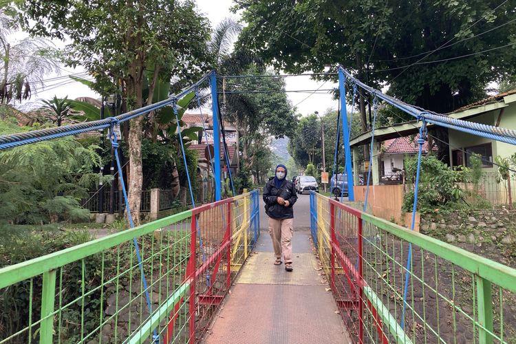 Seorang wisatawan sedang berjalan di atas Jembatan Gantung Sempur, tepatnya di salah satu titik Sungai Ciliwung yang memiliki pesona indah, meski di beberapa area terlihat banyak tumpukan sampah plastik, Kota Bogor, Senin (24/5/2021).
