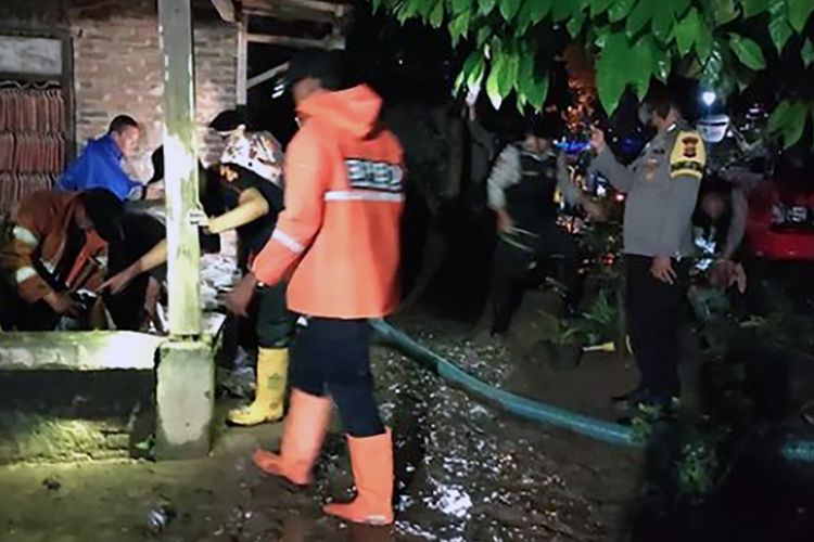 Petugas kepolisian dan BPBD membersihkan sisa banjir yang terjadi di Pekon (desa) Fajar Agung, Pringsewu, Sabtu (22/10/2022) malam. Sebanyak tiga pekon terdampak banjir setelah hujan melanda wilayah itu sejak pukul 15.00 WIB hingga 21.00 WIB.