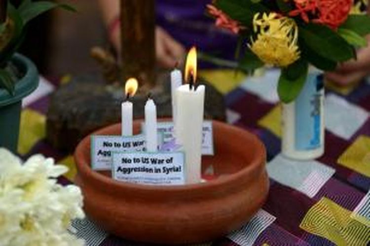 Warga Filipina memasang tulisan anti-Amerika Serikat dan menyalakan lilin dalam doa bersama di Manila, 7 September 2013. Paus Fransiskus menyerukan kepada dunia agar puasa dan doa bersama untuk perdamaian Suriah dan menolak intervensi militer.