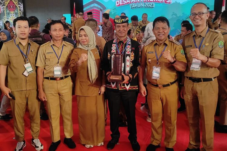Kades Sei Limau Pulau Sebatik, Mardin (tengah mengenakan pakaian adat) menunjukkan penghargaan KPK atas torehan Desa Sei Limau sebagai Desa Anti Korupsi 2023