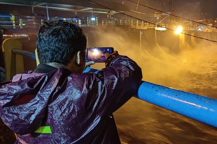 Seorang warga sedang mengamati ketinggian air di Bendung Katulampa Bogor, Minggu (9/10/2022) malam. Bendung Katulampa mengalami kenaikan status level kewaspadaan menjadi siaga satu setelah hujan deras mengguyur wilayah Bogor sejak sore hingga malam.