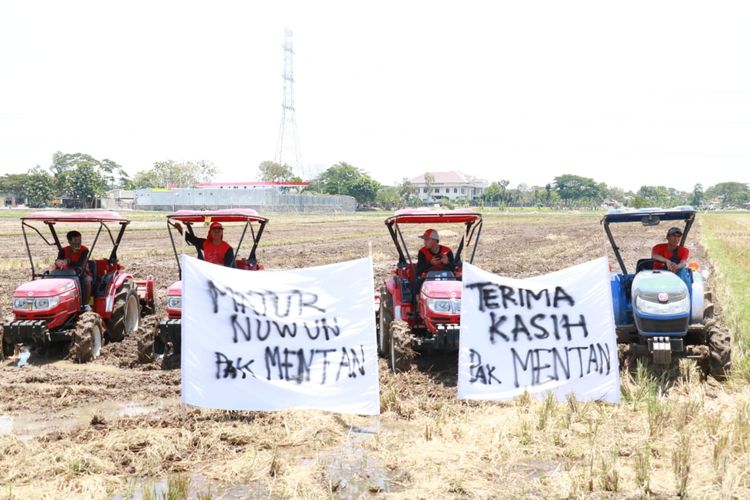 Beberapa petani sedang mengibarkan spanduk bertuliskan tanda terima kasih kepada Menteri Pertanian.