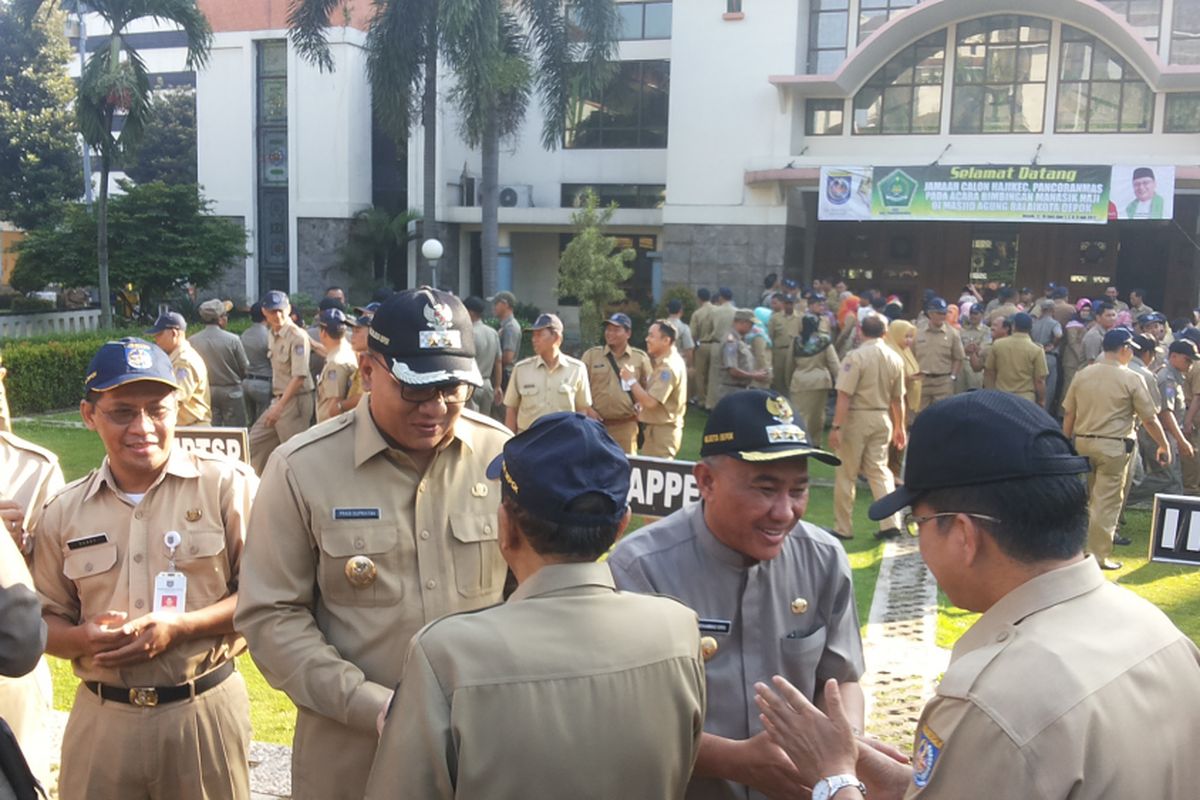 Wali Kota Depok Idris Abdul Shomad beserta wakilnya, Pradi Supriyatna saat bersalam-salaman dengan para PNS pasca libur lebaran di halaman Balai Kota Depok, Senin (3/7/2017).