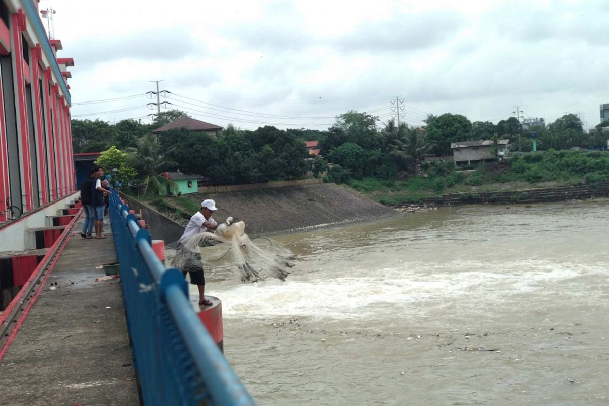 Iwan (42), warga Koang Jaya, Tangerang Kota sedang memancing dengan jala di Bendung Pasarbaru, Rabu (28/2/2018).