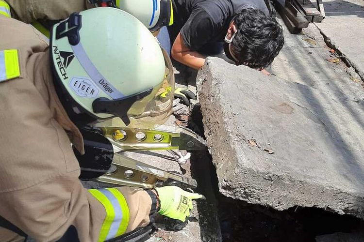 Petugas mengambil headset yang jatuh ke gorong-gorong di kawasan Jalan Raya Bogor, Ciracas, Jakarta Timur, Selasa (8/9/2020)