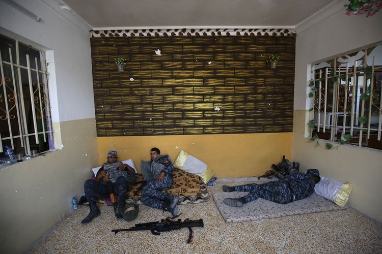Beberapa anggota militer Irak beristirahat sejenak dalam gerak maju merebut kota Mosul dari tangan ISIS.