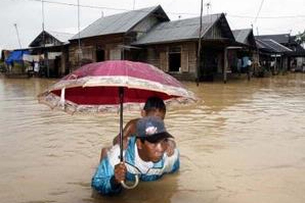 Abdul Sain bersama anaknya melintasi banjir luapan Sungai Basung di Kampung Basung, Kecamatan Cempaka, Banjarbaru, Kalimantan Selatan, Rabu (5/3).