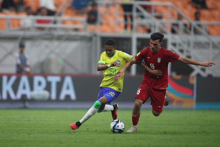 Penyerang timnas U17 Brasil, Estevao Willian (kiri), berebut bola dengan gelandang timnas U17 Iran, Abolfazl Zamani. Laga Brasil vs Iran pada matchday pertama Grup C Piala Dunia U17 2023 tersebut digelar di Jakarta International Stadium (JIS), Sabtu (11/11/2023) malam WIB.