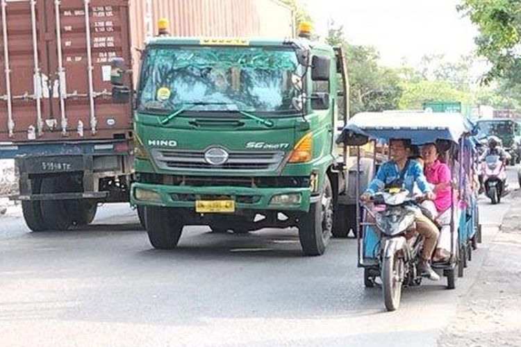 Sejumlah odong-odong membawa penumpang ibu-ibu dan anak-anak menantang maut dengan beroperasi di antara truk kontainer di Jalan Raya Cilincing, Kecamatan Cilincing, Jakarta Utara, Rabu (27/7/2022).  