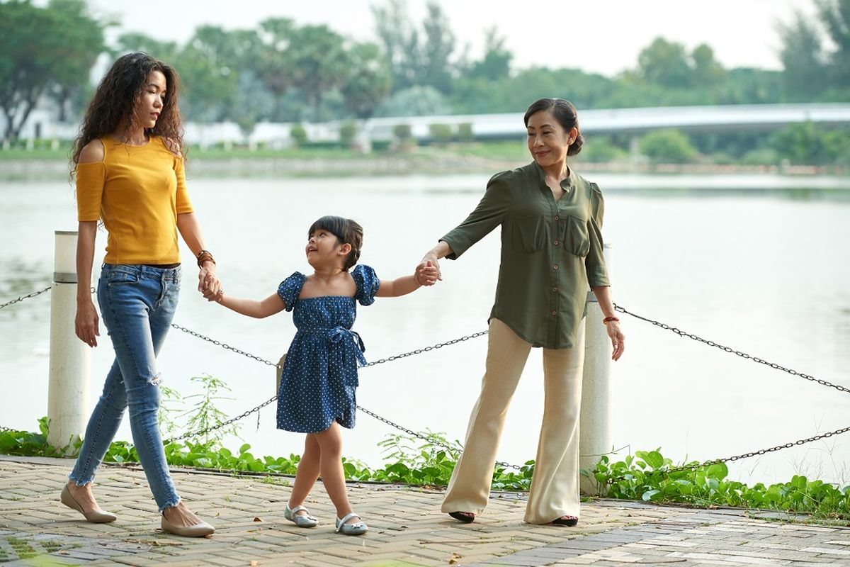 Ilustrasi ibu, anak, dan cucu sedang berjalan-jalan di taman.