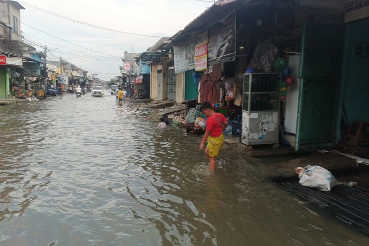 Anak-anak bermain air di jalanan yang banjir di Kabupaten Bekasi.