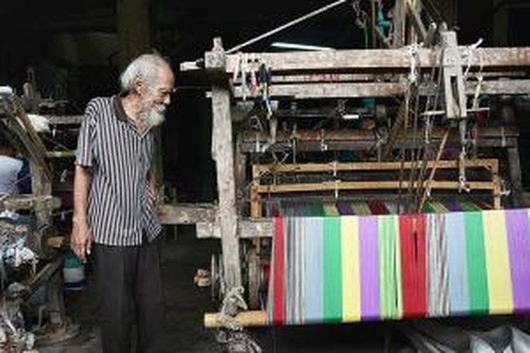 Raden Rachmad memperhatikan pembuatan kain tenun lurik di tempat usaha miliknya di Kecamatan Pedan, Klaten, Jawa Tengah. Sejumlah industri tenun tradisional di kawasan sentra penghasil kain tenun lurik berupaya bertahan di tengah membanjirnya produk buatan pabrik modern di pasaran.