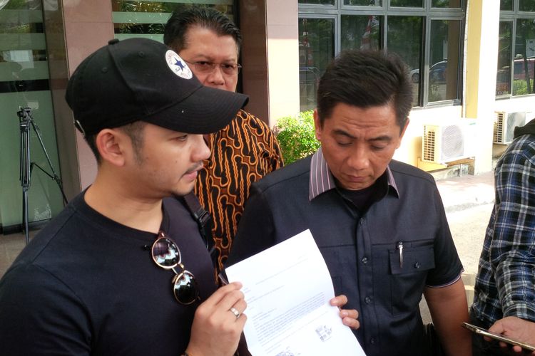 Suami Dewi Perssik, Angga Wijaya, memperlihatkan surat permohonan pencabutan laporan Rosa Meldianti terhadap istrinya di Polres Jakarta Selatan, Rabu (17/7/2019). Angga didampingi oleh kuasa hukum Dewi, Sandy Arifin.