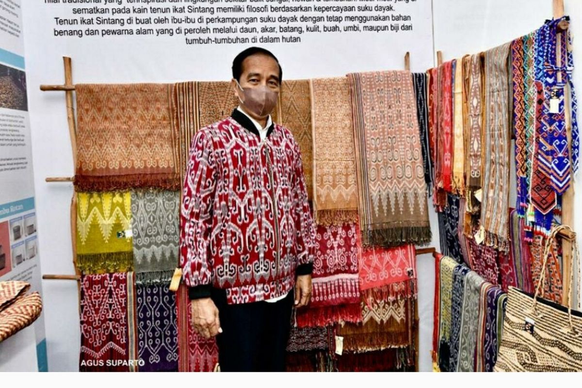 Presiden Jokowi saat berfoto mengenakan jaket bomber warna merah yang dibelinya dari UMKM di Sintang, Rabu (8/12/2021). 