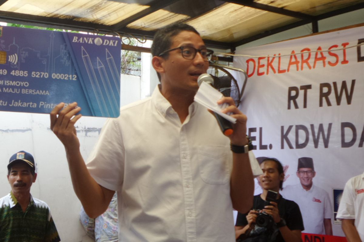Calon wakil gubernur DKI Jakarta Sandiaga Uno memperlihatkan contoh KJP (Kartu Jakarta Pintar) Plus saat memberi pengarahan kepada relawan di Ciracas, Jakarta Timur, Minggu (26/3/2017).