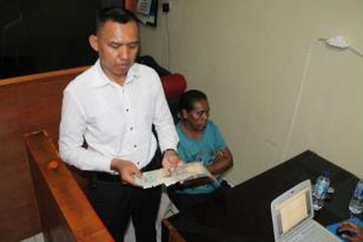 Kanit Tipiter, Ipda Jamari (kiri) sedang menunjukan uang palsu kepada wartawan. Sementara pelaku Mariance Adriana Faot (43) mengenakan baju biru, sedang diperiksa penyidik